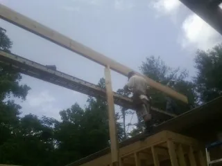 Carpenter setting a ridge beam over a new addition frame — Ice Dam Removal by Roofing Brothers in Abita Springs
