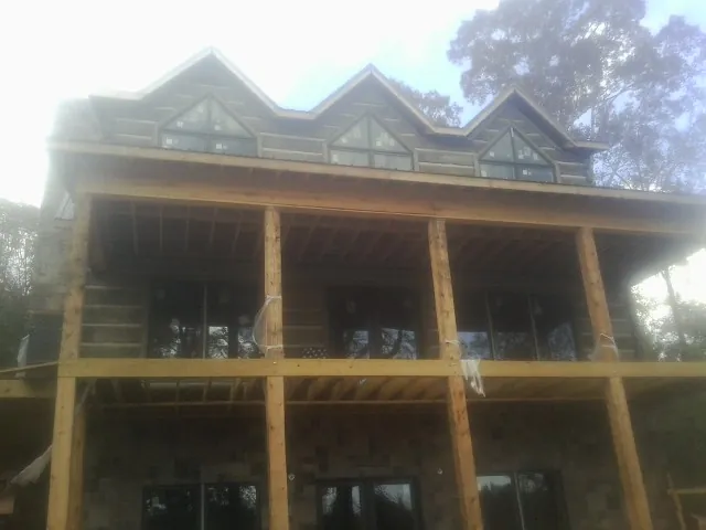 Dormers and porch framing on a large log home under construction — Roof Coating work by our crew in Abita Springs
