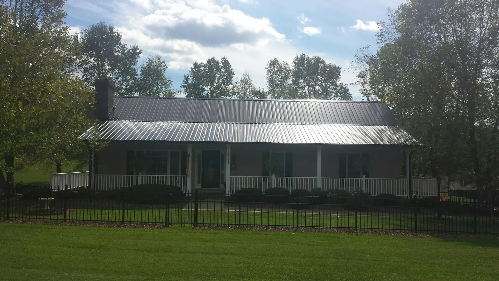 Gray metal roof on a brick ranch with a full width front porch — Gutter Guard Installation work by our crew in Abita Springs